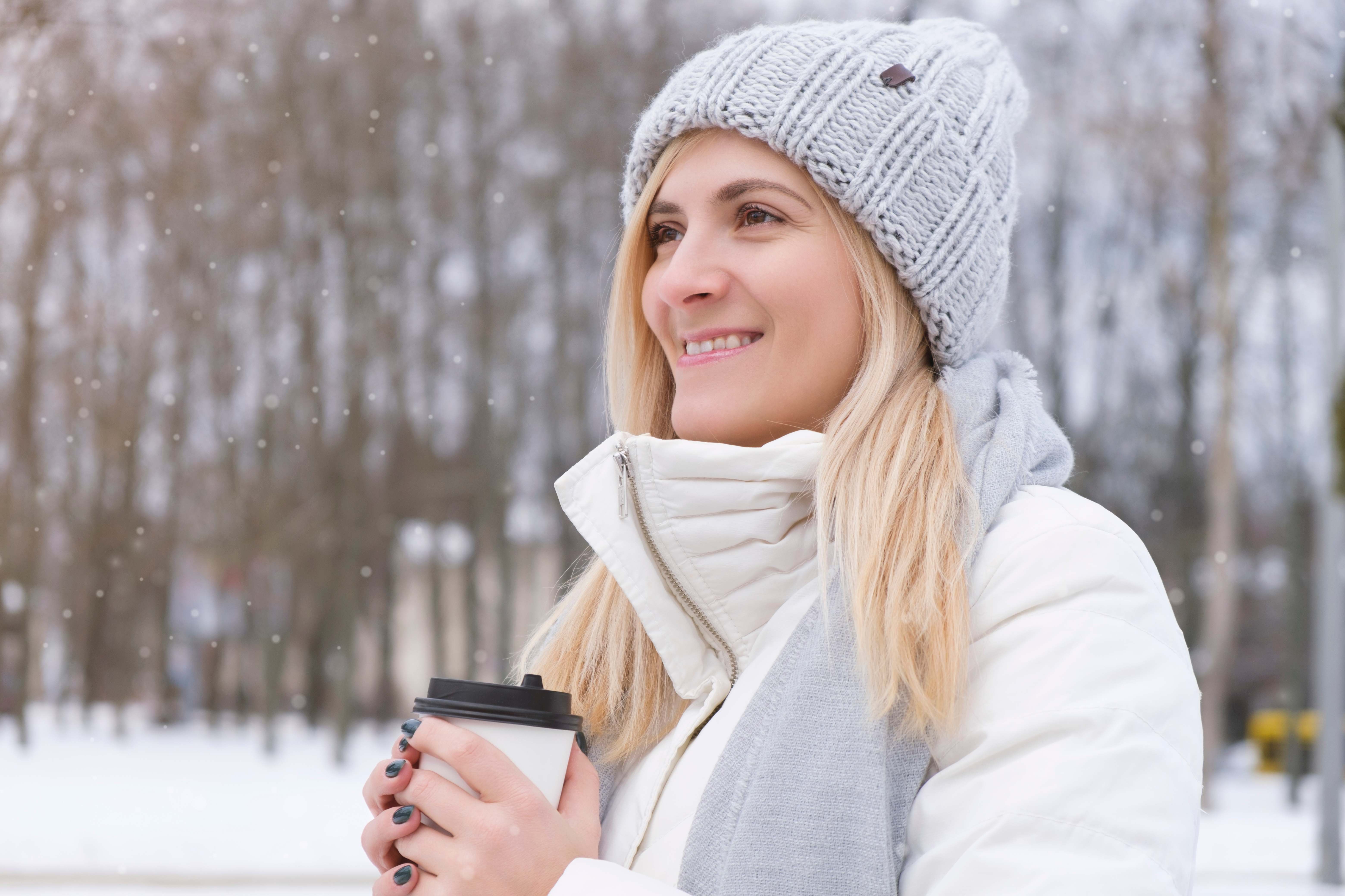 A woman enjoys some alone time outdoors with a cup of coffee on a cold February afternoon.