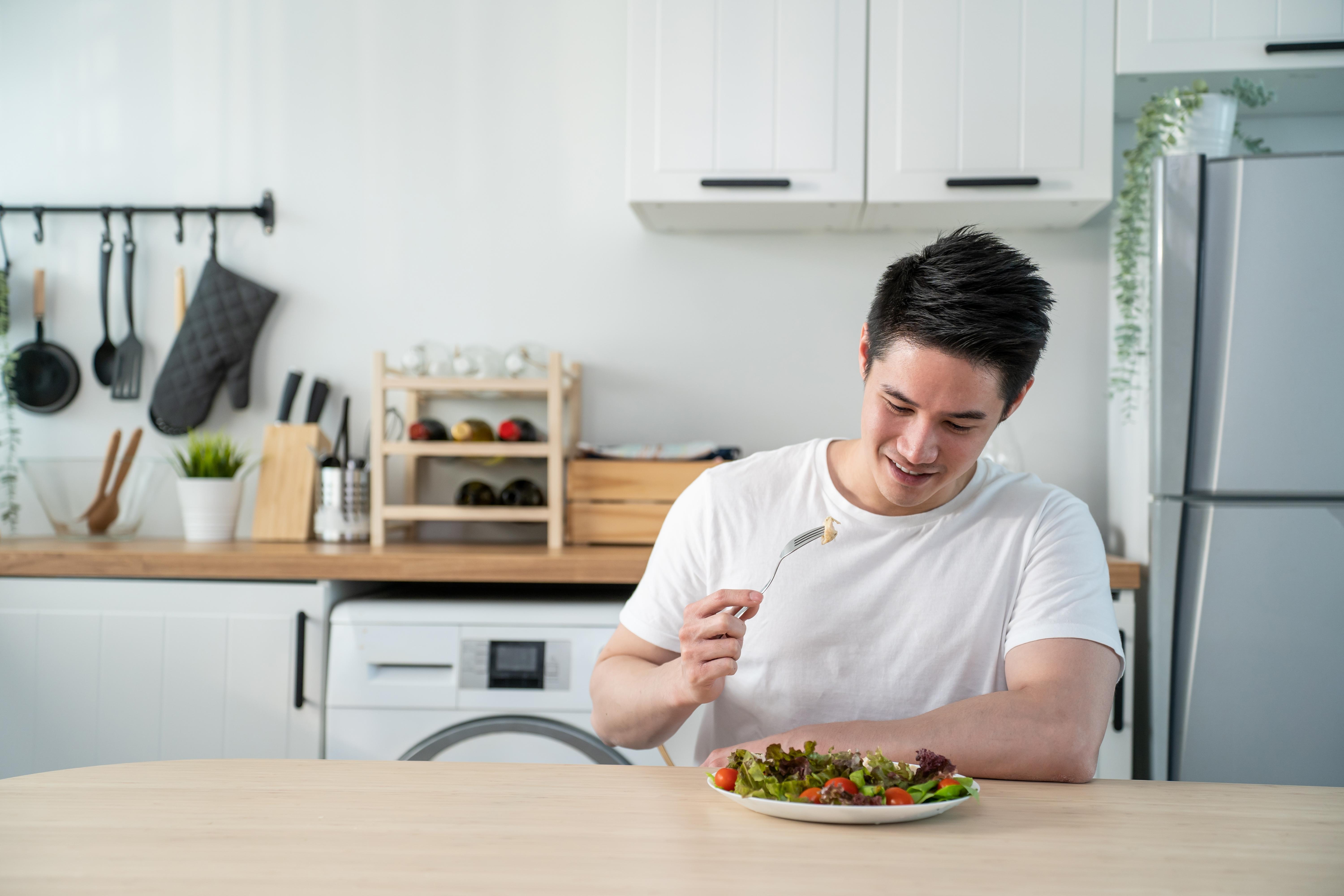 A single man enjoys a healthy gourmet meal alone in his kitchen. 