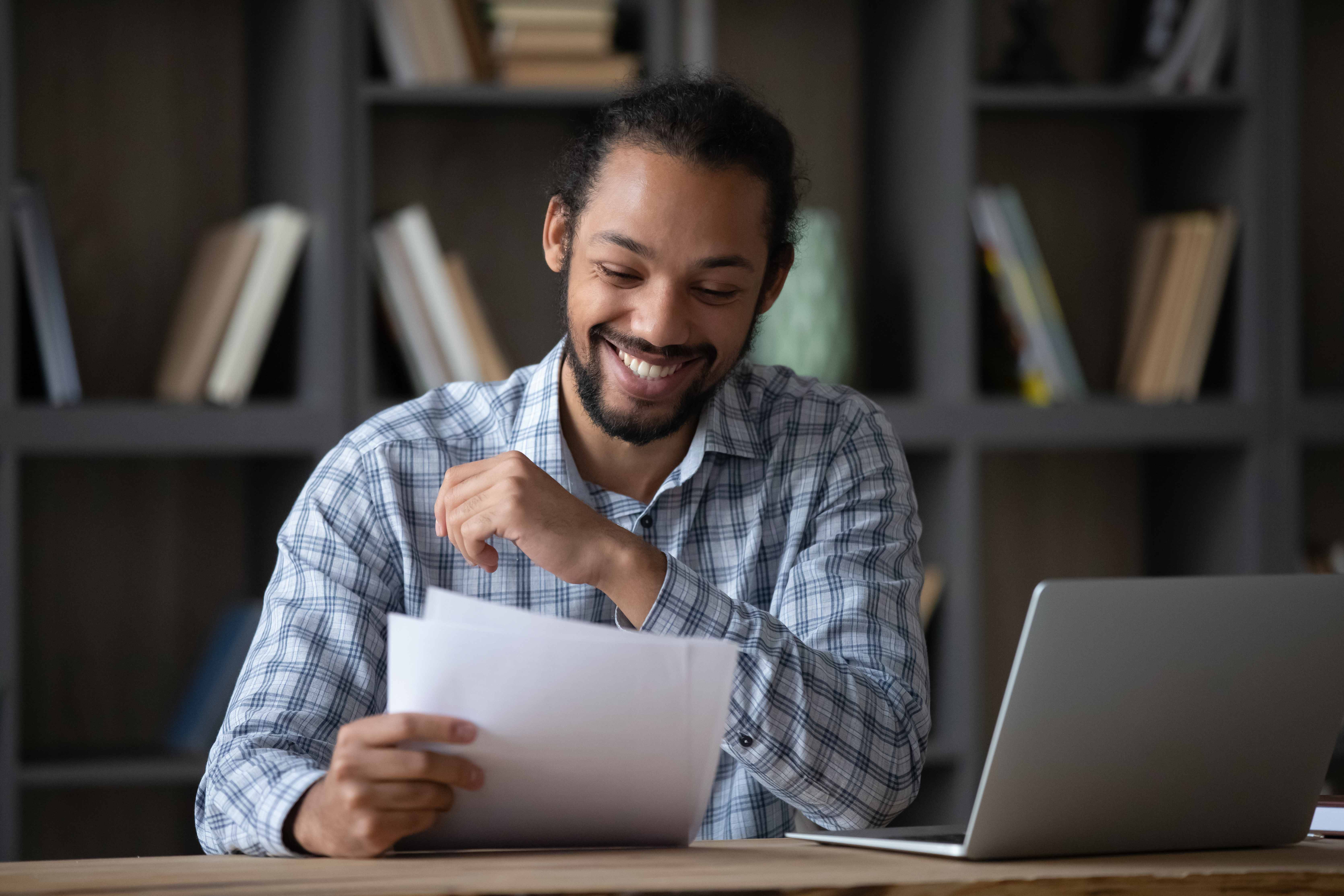 A man smiles as he reads a positive, affirming letter he has written to himself. 