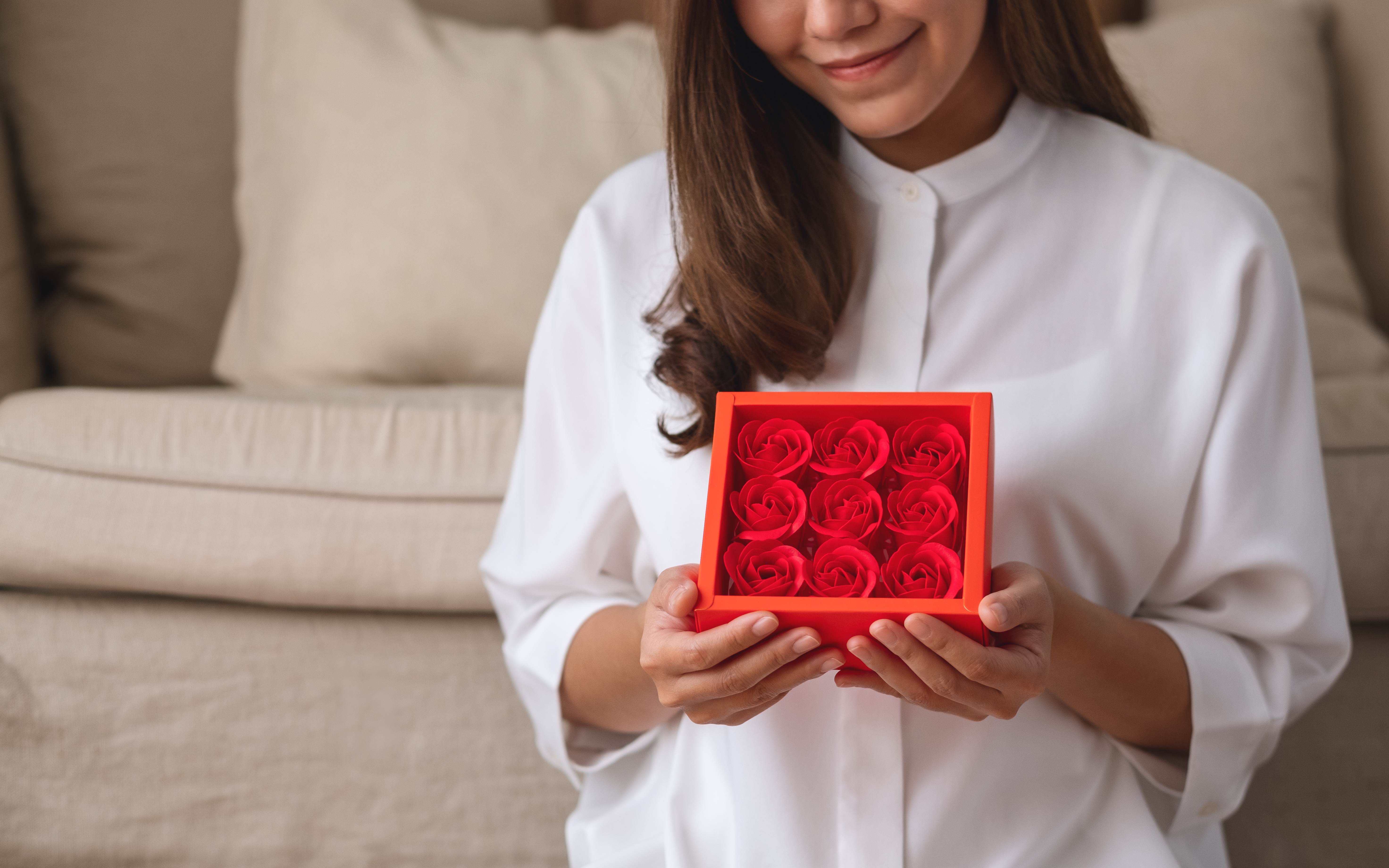 A woman receives a box of forever roses from her partner. 
