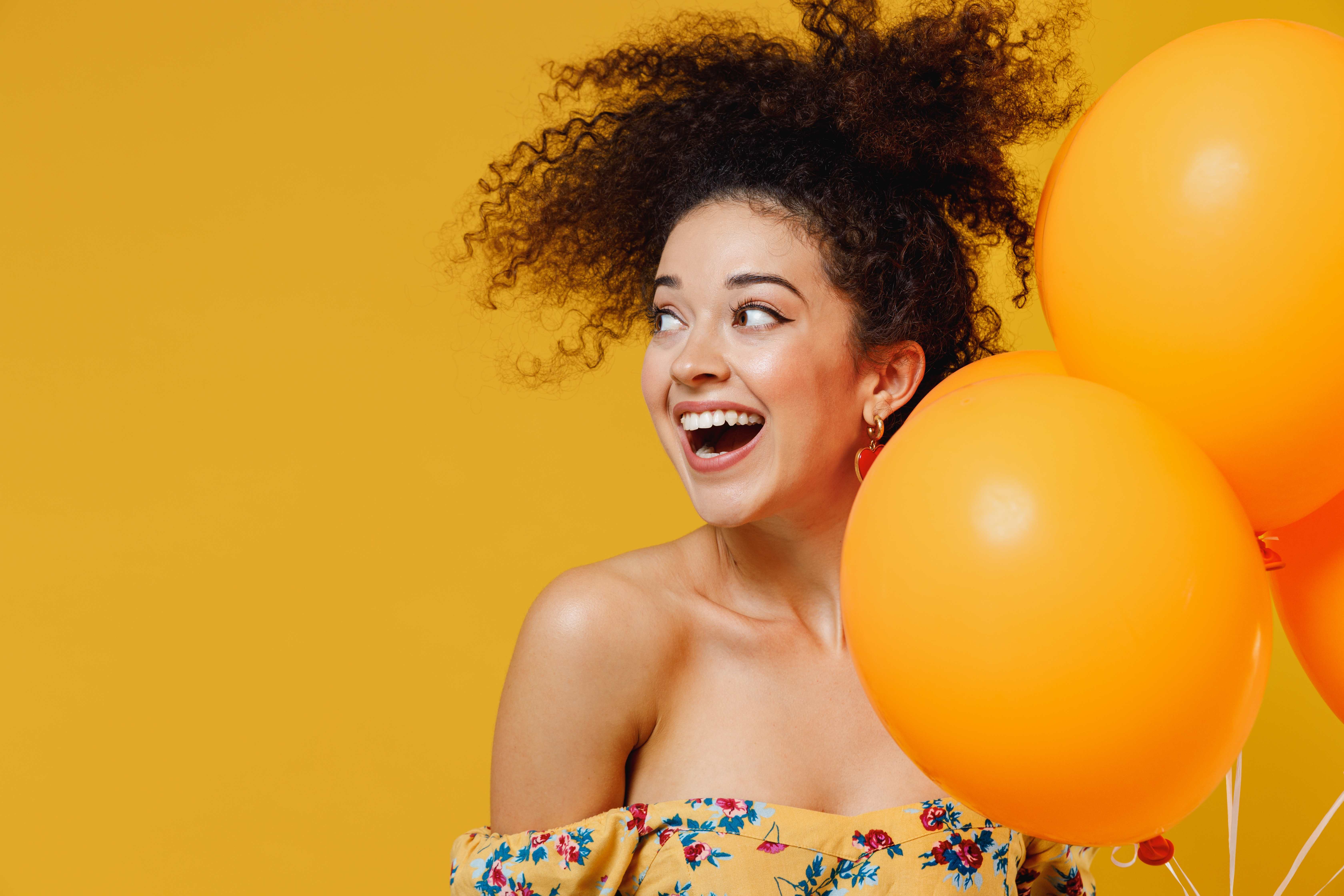 An excited Aquarius woman receives yellow balloons on her birthday. 