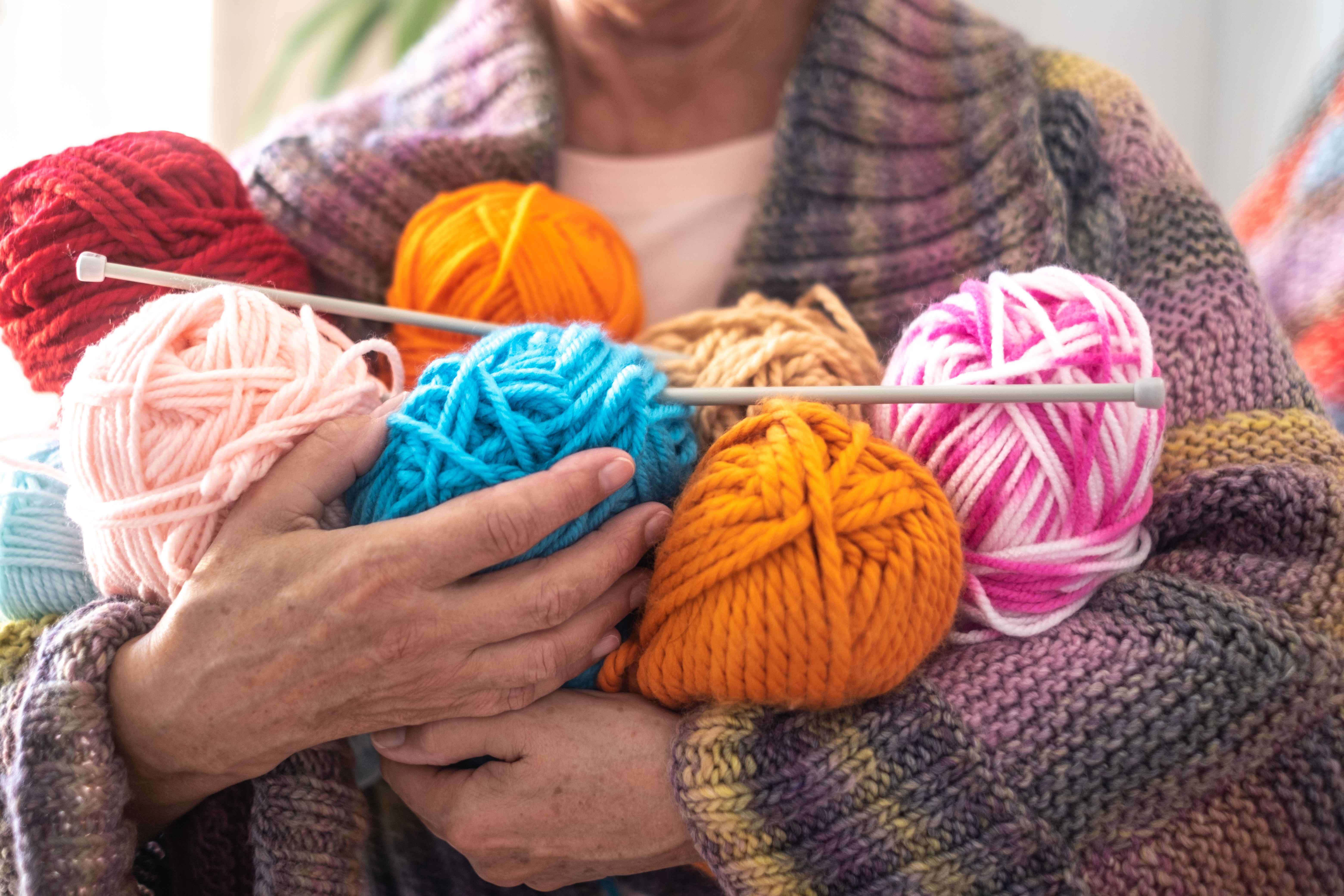 A retired woman has her arms full with yarn for crafting. 