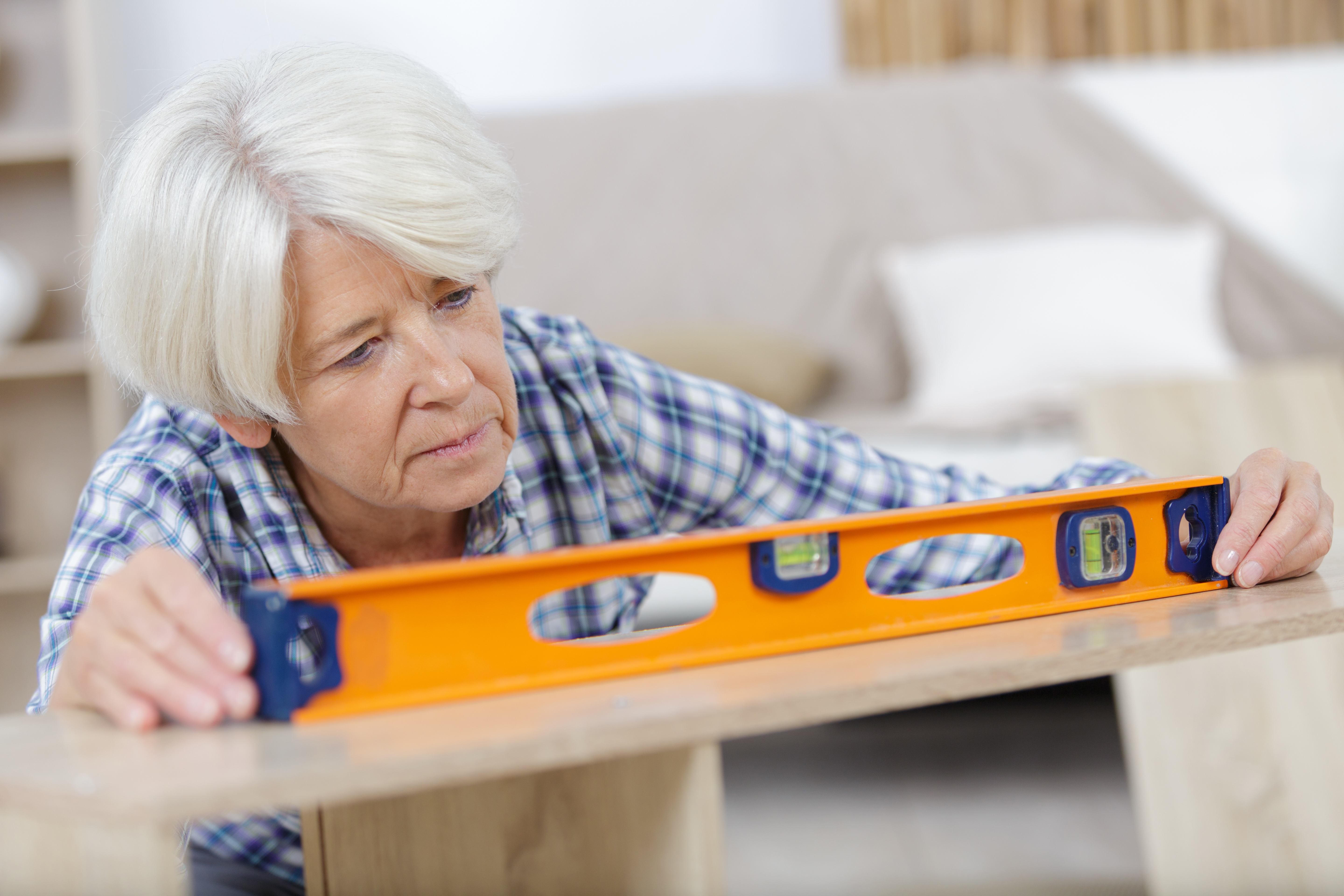 A senior woman uses a level for a home improvement project after retirement.