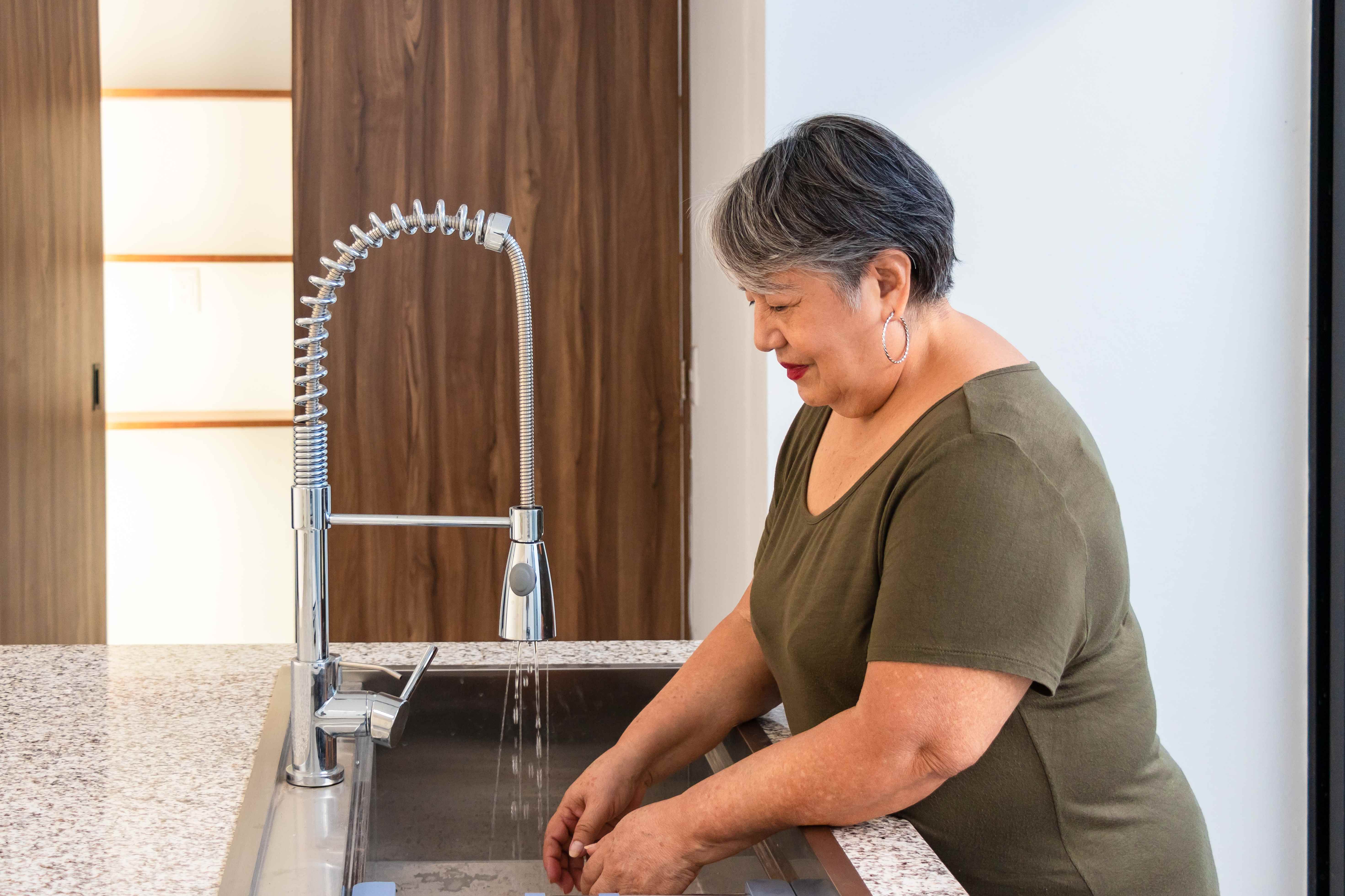 A retired woman washes her hands at home. 