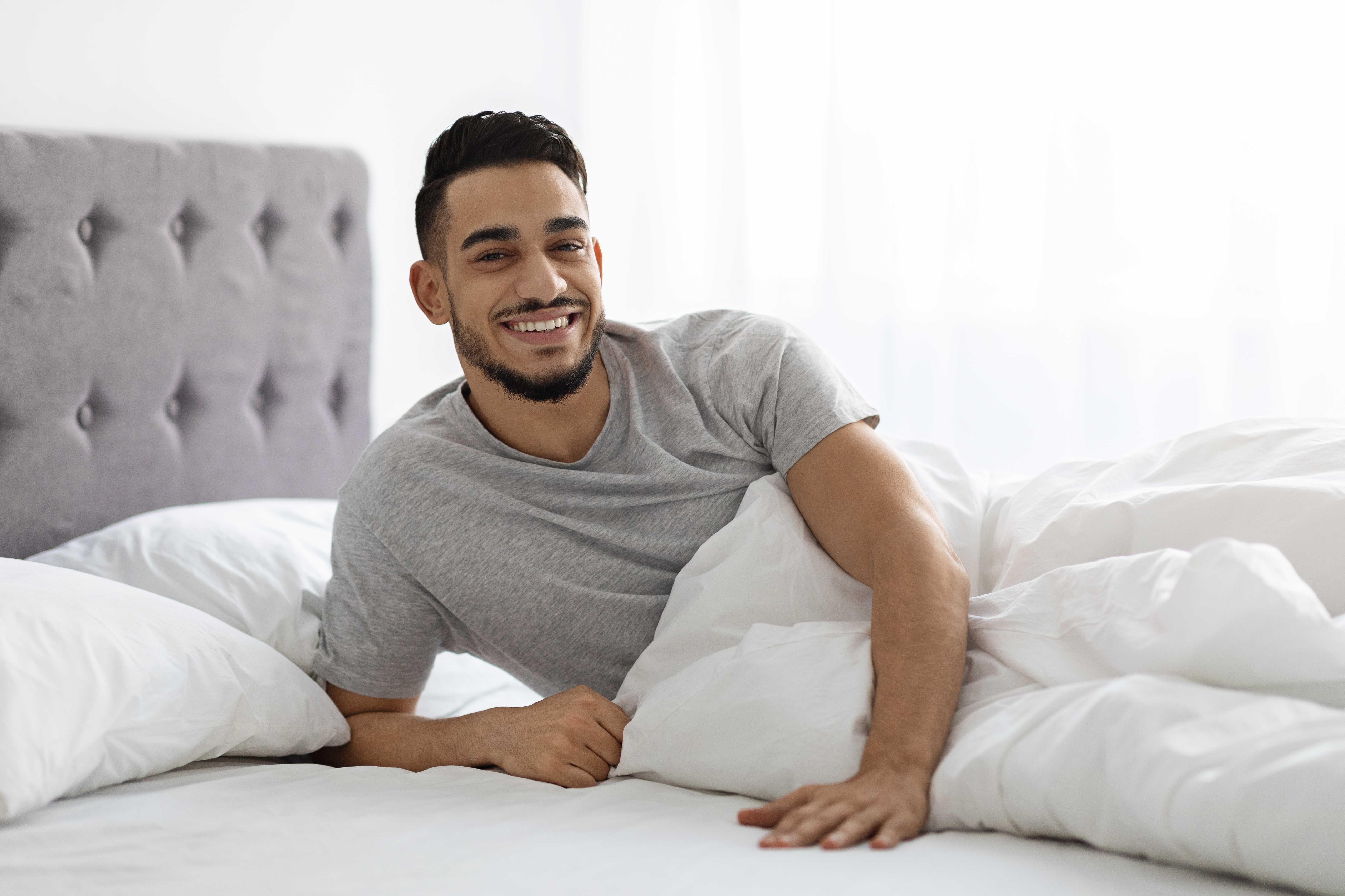 A man enjoys a lazy morning relaxing in bed with his luxurious new sheets.