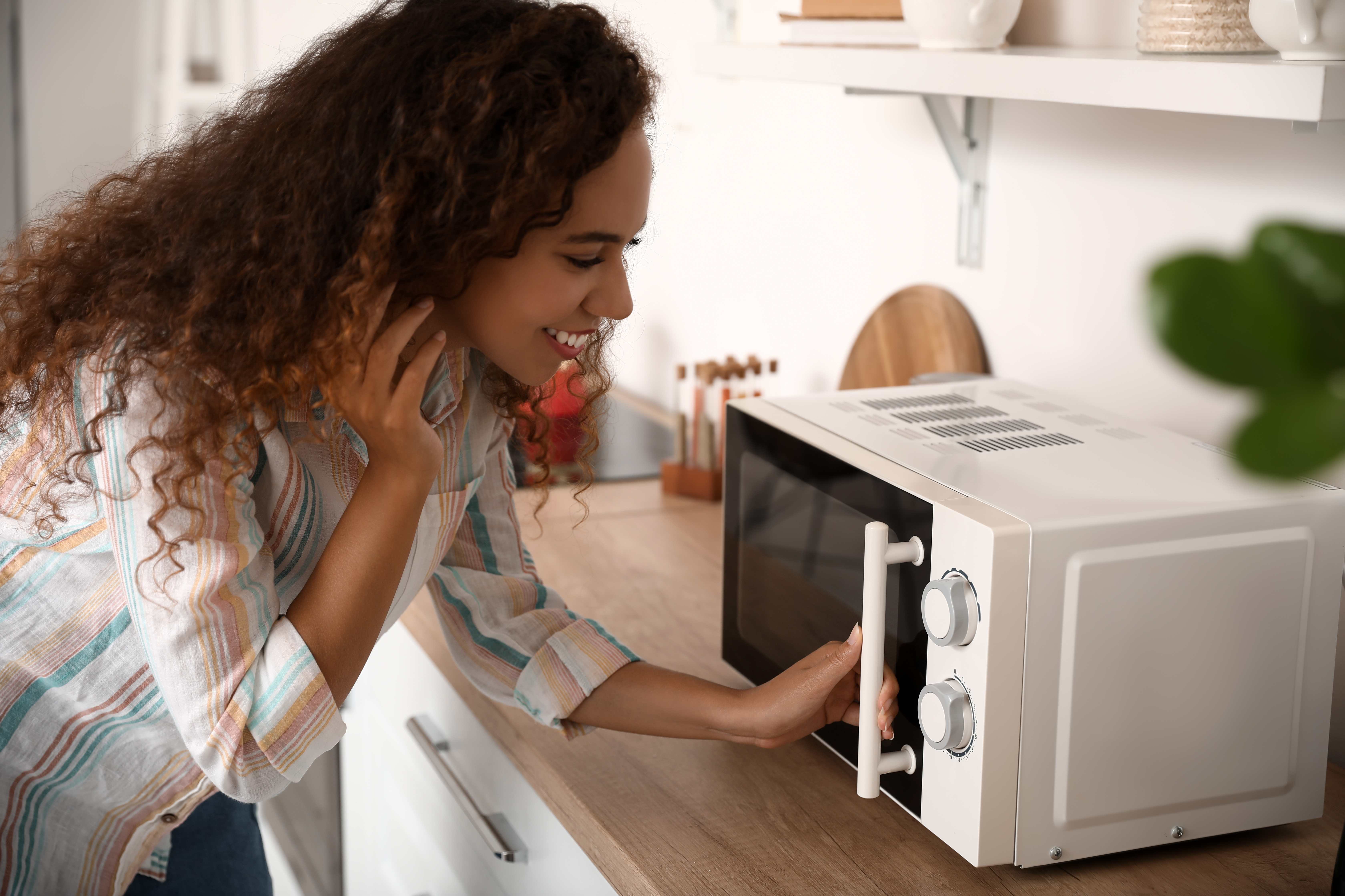 A busy young mother microwaves a prepared meal for her family.