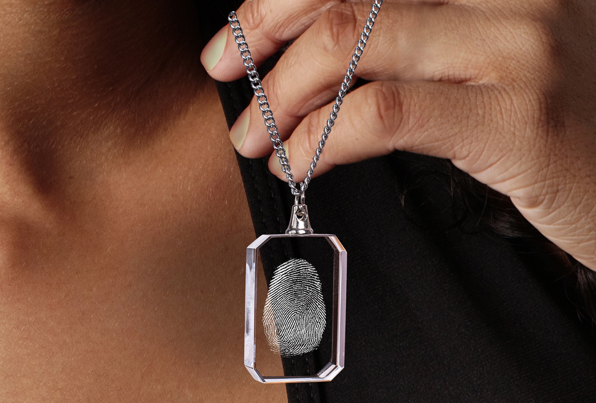 A woman shows off the engraved fingerprint necklace she got as a gift from a friend.