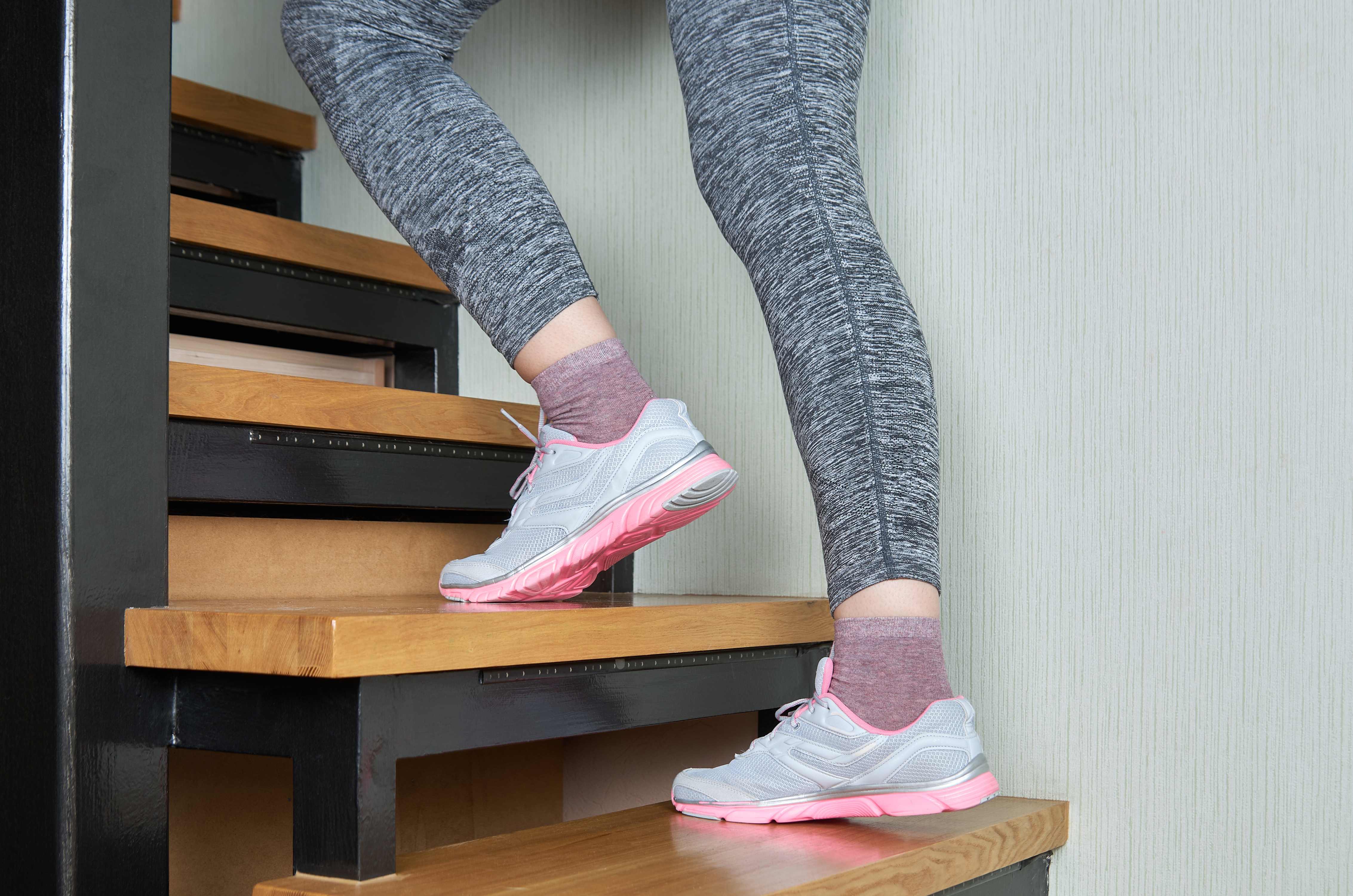 An active woman walks upstairs in her comfortable shoes.