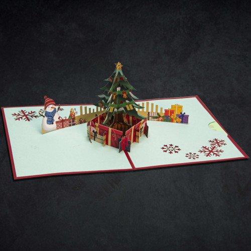 An open holiday greeting card with a pop–up Christmas tree scene inside