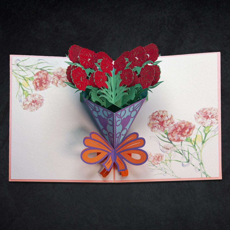 An open greeting card with a pop-up 3D clover bouquet with orange ribbon inside