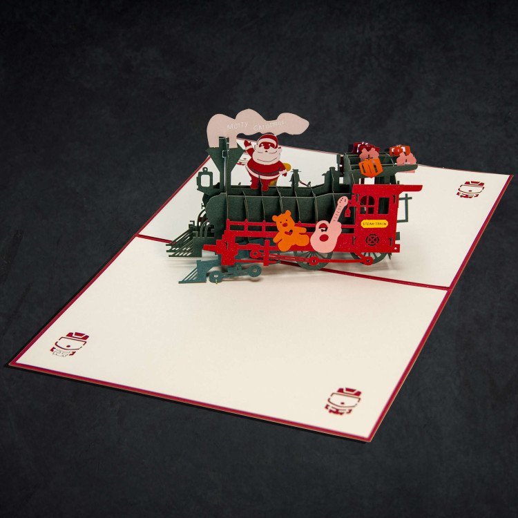 An open Christmas greeting card with a 3D pop-up train inside
