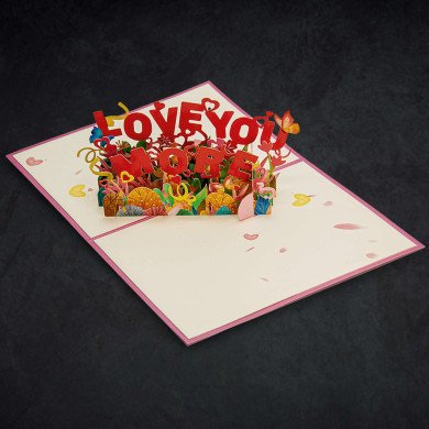 An open greeting card that says “Love You More” in pop-up letters